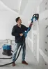 A man is using a long-reach sander on a wall in a room under construction. Podgląd zdjęcia produktu