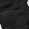A close-up view of a black outdoor winter pant with a zippered pocket and a red and black logo. Produktbild-Vorschau