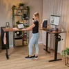 A woman is working at a standing desk in a home office setting. Produktbild-Vorschau