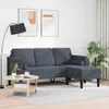 A dark gray sofa set with cushions is arranged in a living room setting, next to a coffee table and a floor lamp. Produktbild-Vorschau