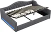 A grey upholstered daybed with its mattress support frame extended, revealing storage space underneath and blue LED lighting along the side. Náhľad obrázku produktu