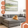 A Pomeranian dog sits on a gray sectional sofa in a living room, with a large abstract painting on the wall above it. Podgląd zdjęcia produktu
