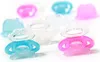 Several baby pacifier-shaped teethers in pink and blue colors are arranged on a white background. Produktbild-Vorschau