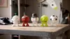 Five decorative figures are lined up on a wooden table. Produktbild-Vorschau