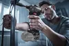 A man is using a cordless impact wrench to tighten a bolt on a metal structure. Produktbild-Vorschau