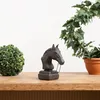 A dark brown horse head bust sculpture sits on a wooden table next to a green spherical topiary and a potted ivy plant. Produktbild-Vorschau