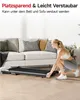 A woman is shown interacting with a foldable treadmill next to a sofa in a living room. Produktbild-Vorschau