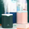 Three humidifiers in different colors (white, green, and pink) are displayed on pedestals, with mist emanating from them. Náhled obrázku produktu