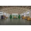 A warehouse interior with a green chain-link fence enclosure containing boxes on pallets, surrounded by stacks of boxes and material handling equipment. Produktbild-Vorschau
