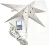A white paper star lantern with brown star cutouts and dots, along with its power cord and a small box containing a light bulb and instructions, is laid out on a white surface. Produktbild-Vorschau