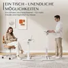 A woman sits in a chair reading a book next to a small white table, while a man stands at a taller white table working on a laptop. Voir les images du produit