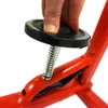 A close-up shot of a hand pressing down on a black cap attached to a spring, which is part of a red metal device. Anteprima dell’immagine prodotto