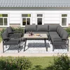 An outdoor patio set with a sectional sofa, chairs, and a coffee table, set on a rug in front of a house. Produktbild-Vorschau
