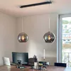 Two pendant lights hanging over a dining table with a laptop and monitor on it. Voir les images du produit
