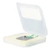 A small metal plate with a green string is presented in an open white plastic case with foam padding. Produktbild-Vorschau