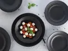 A top-down view of black plates with a small salad in the center. Náhľad obrázku produktu