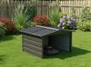A robot lawn mower is parked inside a metal garage in a garden setting. Produktbild-Vorschau