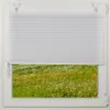 A white pleated blind is partially lowered over a window, revealing a field of green grass and wildflowers. Produktbild-Vorschau
