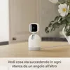 A white Blink Mini Pan-Tilt camera is placed on a wooden table, with a vase of flowers in the background. Produktbild-Vorschau