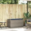 An outdoor storage bench with a cushion sits on a patio next to a wooden fence and a small folding table. Náhľad obrázku produktu