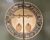 A close-up of a decorative brass latch and handles on a round wooden cabinet door with intricate carvings. Voir les images du produit