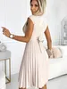 A woman wearing a beige dress in a studio setting. Produktbild-Vorschau