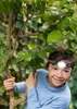 A young boy wearing a headlamp is climbing a tree in a garden. Produktbild-Vorschau