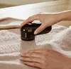 A person is using a fabric shaver on a piece of clothing. Produktbild-Vorschau