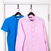 Two shirts are hanging on hangers on a door. Podgląd zdjęcia produktu