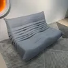A gray sofa is placed on a rug in a room with white walls. Anteprima dell’immagine prodotto