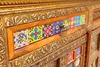 A close-up view of a wooden sideboard with decorative tiles and ornate metalwork. Produktbild-Vorschau