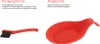 Links ist eine kleine schwarze Reinigungsbürste mit rotem Griff zu sehen, rechts ein roter Löffelhal Produktbild-Vorschau