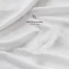 A close-up of white fabric with a feather and text overlay. Produktbild-Vorschau