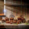 A collection of ceramic fermentation crocks and pots arranged on a burlap-covered table in a rustic setting, with sunlight streaming through wooden beams. Voir les images du produit