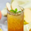 A close-up of a glass of iced tea with peach slices and mint leaves. Produktbild-Vorschau