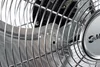 A close-up view of the fan blades and grille of a silver floor fan. Voir les images du produit