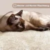 A Siamese cat is lying on a soft, fluffy beige surface, possibly a cat tree or bed. The cat is relaxed and appears comfortable. Podgląd zdjęcia produktu