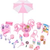 A collection of pink dollhouse accessories, including a table, chairs, umbrella, and various food and drink items, arranged on a white background. Náhľad obrázku produktu