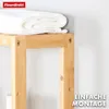 A close-up of a wooden shelf with a white towel on it, against a light gray wall. Náhled obrázku produktu