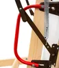A close-up view of the mechanical components of a folding attic ladder, including a red metal handle, brown metal brackets, and a silver spring, attached to wooden ladder rungs. Podgląd zdjęcia produktu