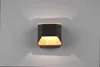 A modern black and wood wall light is mounted on a gray wall, casting light upwards and downwards. Podgląd zdjęcia produktu