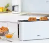 A white BRAUN toaster with two slices of toast is shown on a kitchen counter, with a bowl of jam and croissants in the foreground. Náhled obrázku produktu