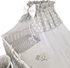 A close-up view of a baby crib with bedding and a canopy. Produktbild-Vorschau