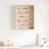 A wooden display shelf filled with miniature toy cars, mounted on a white wall. Below the shelf, on a white surface, are wooden toy train pieces and a framed picture of a dog. Podgląd zdjęcia produktu