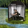 A man is fishing from a portable shelter on the bank of a lake. Anteprima dell’immagine prodotto