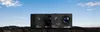 Two black action cameras are placed on a rocky surface with a blue sky and clouds in the background. Produktbild-Vorschau