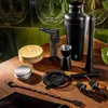 A collection of bar tools and a blow torch are arranged on a wooden table in front of a tiled wall. Voir les images du produit