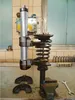 A car suspension spring compressor tool set on a workbench in a workshop. Voir les images du produit