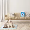 A cat and a husky dog sit on a training pad in front of a couch, with a bag of pet supplies on the couch. Produktbild-Vorschau
