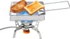 A portable toaster is shown with two slices of toast on top, heated by a blue flame from a camping stove. Náhľad obrázku produktu
